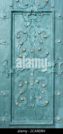 Magnifiques motifs forgés sur une porte de couleur émeraude. Gros plan. Banque D'Images