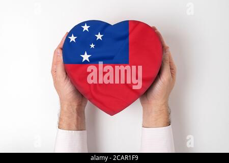 Drapeau des Samoa sur une boîte en forme de coeur dans les mains d'un homme. Arrière-plan blanc Banque D'Images