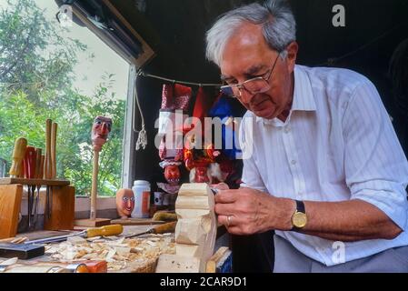 Le maître marionnette John Haynes sculptant une tête de M. Punch dans son studio. Angleterre, Royaume-Uni. 1990 Banque D'Images