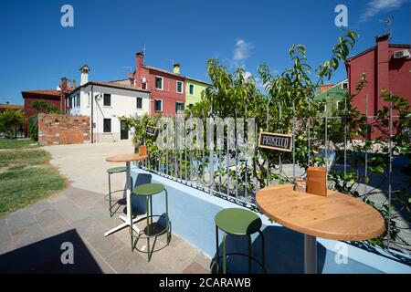 Île de Burano, lagune vénitienne, Venise, Italie, un bar en plein air avec terrasse avec spritz avec les maisons traditionnelles colorées du village Banque D'Images