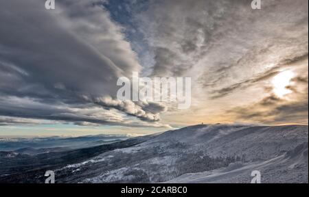 De lourds nuages orageux, de la neige tombant en hiver, avec de faibles nuages de vent de foehn descendant au-dessus de Labski Szczyt, montagne dans le parc national de Karkonosze, Pologne Banque D'Images