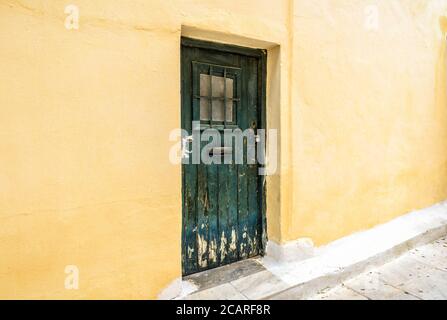 Ancienne porte de bâtiment résidentiel dans le quartier de Plaka, Athènes, Grèce. Plaka est une attraction touristique d'Athènes. Maison traditionnelle avec mur jaune et grun Banque D'Images