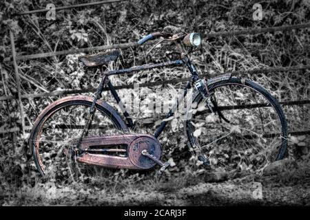 ancienne bicyclette abandonnée penchée contre la clôture avec effet désaturé Banque D'Images