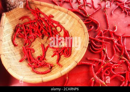 Poivrons rouges épicés ou en chinois la jiao sur un sol rouge et sur un panier de bambou dans la province du Sichuan en Chine. Banque D'Images