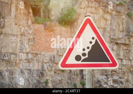 Panneau de signalisation routière attention chute de roche, sur fond de roche Banque D'Images