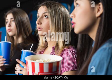 Des amis. Gros plan d'une belle femme qui regarde un film à couper le souffle ensemble au cinéma Banque D'Images
