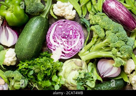 Vue de dessus ensemble brut de légumes verts, rouges et violets sur fond de bois foncé Banque D'Images