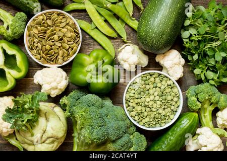 Vue de dessus ensemble brut de légumes verts et violets et protéines pour végétariens sur fond de bois foncé Banque D'Images