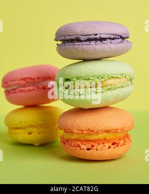 pile de macarons cuits sur fond vert jaune, délicieux dessert à base de farine d'amande, gros plan Banque D'Images