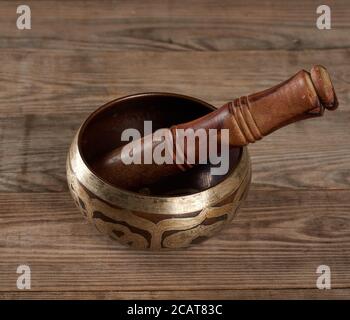 Tibétain chantant bol en cuivre avec un clapper en bois sur une table en bois brun, objets pour la méditation et médecine alternative, gros plan Banque D'Images