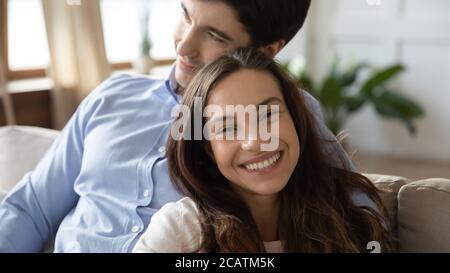Un jeune couple caucasien souriant profite d'un doux moment à l'intérieur.