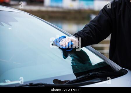 Nettoyage à la main du pare-brise d'une voiture à l'aide d'un chiffon en microfibre Banque D'Images