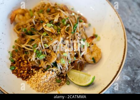 Cuisine de rue traditionnelle thaïlandaise, nouilles Pad Thai sur une plaque blanche et une table en pierre de marbre. Banque D'Images