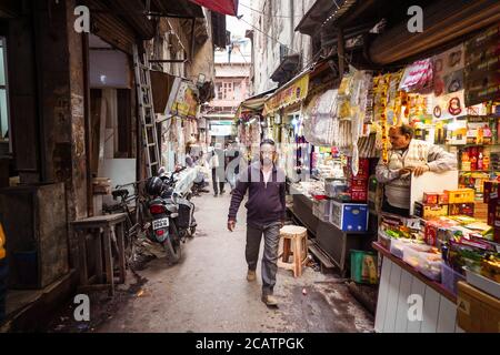 Agra / Inde - 22 février 2020 : un homme hindou qui descend une ruelle étroite du centre-ville historique d'Agra avec des boutiques de bazar Banque D'Images