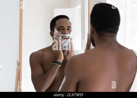 Miroir reflet sourire Afro-américain homme appliquant de la mousse à raser Banque D'Images