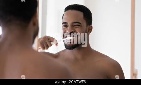 Tête de tir miroir reflet sourire Afro-américain homme nettoyant les dents Banque D'Images