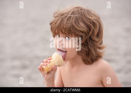 Adorable petit garçon qui se réglisse de grandes crèmes glacées dans un cône de gaufres. Enfant mangeant de glace. Un enfant avec un visage sale mange de la glace. Banque D'Images