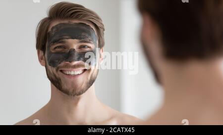 Tête prise de vue portrait souriant homme beau avec masque de charbon noir Banque D'Images