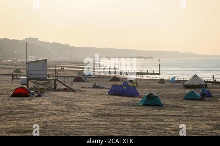 Tentes dressée sur la plage de Bournemouth à Dorset au lever du soleil. Banque D'Images