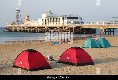 Tentes dressée sur la plage de Bournemouth à Dorset au lever du soleil. Banque D'Images