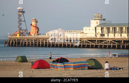 Tentes dressée sur la plage de Bournemouth à Dorset au lever du soleil. Banque D'Images