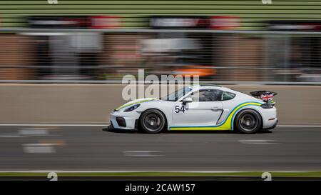 Une photo panoramique d'une voiture de course blanche en circuit sur une piste. Banque D'Images