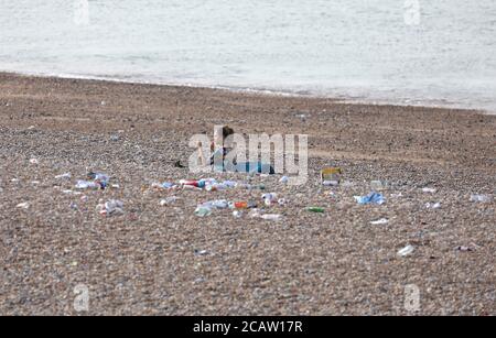 Brighton, Royaume-Uni. 09e août 2020. Une femme s'assoit parmi les détritus sur la plage de Brighton après une journée bien remplie à la station hier. Credit: James Boardman / Alamy Live News Banque D'Images