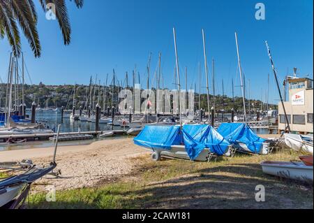 Bateaux couverts de Tarps sur la zone de sable à l'avant De Middle Harbour Yacht Club lors d'un après-midi d'hiver ensoleillé Banque D'Images