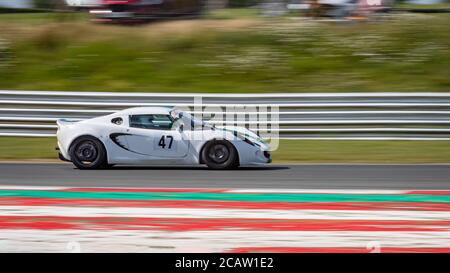 Une photo panoramique d'une voiture de course blanche en circuit sur une piste. Banque D'Images