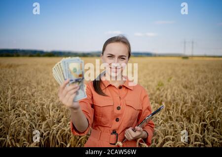 Jeune agriculteur détenant des dollars dans le champ de blé doré. Profitez de l'agriculture pendant la saison de récolte en été. Banque D'Images