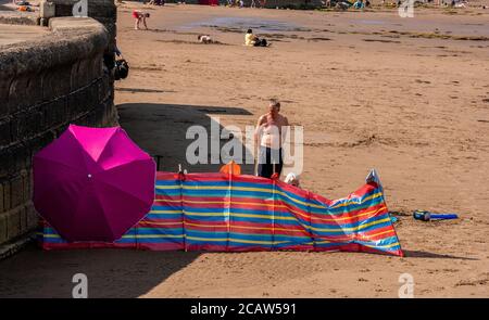Un couple sur la plage de Scarborough vu derrière leur coupe-vent et parasol. Banque D'Images