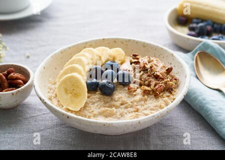 Flocons d'avoine entiers, grand bol de porridge avec banane, bleuets, noix pour le petit déjeuner, Banque D'Images