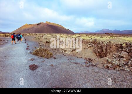 Randonneurs dans un paysage volcanique aride avec le volcan El Cuervo (le Corbeau) dans le parc naturel des Volcans de Los à Lanzarote, îles Canaries, Espagne. Banque D'Images