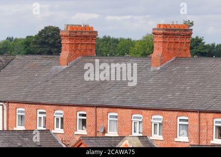 Cheminées en briques au-dessus de maisons mitoyennes à Ashton sous Lyne à Manchester. Banque D'Images