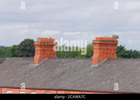 Cheminées en briques au-dessus de maisons mitoyennes à Ashton sous Lyne à Manchester. Banque D'Images