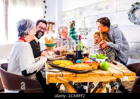 Famille et amis à la maison manger et s'amuser pendant fête de noël - table et décoration et joyeux les gens ensemble appréciant le christ Banque D'Images