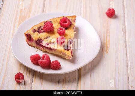 Tarte douce et savoureuse avec fruits de framboise frais et julied dans une assiette, fond de table en bois, vue en angle de gros plan Banque D'Images