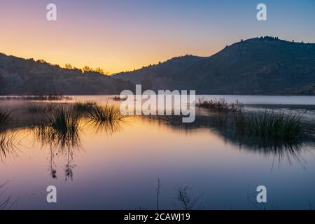 Paysage d'un lac au lever du soleil avec un ciel clair reflété dans l'eau. Banque D'Images