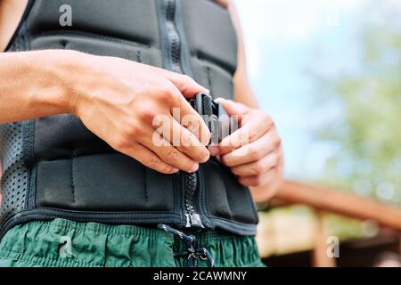 Les mains d'un jeune sportif bouchant la ceinture de sécurité à la taille de veste de sport noire Banque D'Images