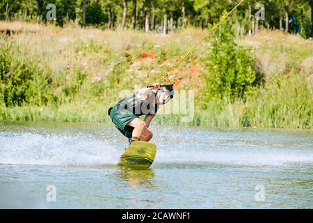 Jeune homme contemporain se déplaçant à la planche de surf tout en tenant par la poignée avec corde Banque D'Images