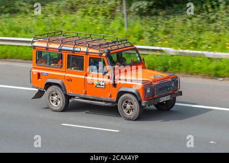 2003 Orange Land Rover Defender 110 TD5 County G4 Challenge ; une compétition mondiale d'aventure. Circulation des véhicules véhicules en mouvement, 4x4 véhicules conduisant le véhicule sur les routes du Royaume-Uni, les moteurs, l'automobile sur le réseau autoroutier M6. Banque D'Images