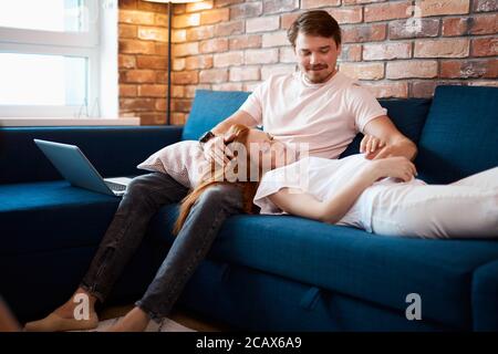homme beau et prudent avc ventre de femme enceinte, couple marié passer le week-end à la maison, se reposer. homme et femme en tenue domestique, pyjama Banque D'Images