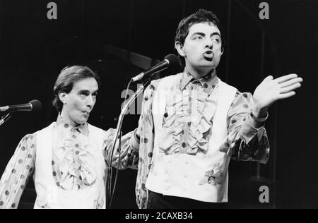 LA NOUVELLE REVUE écrite par Richard Curtis, Ben Elton & Rowan Atkinson Music: Howard Goodall design: Will Bowen Lighting: Mark Henderson l-r: Angus Deayton, Rowan Atkinson Shaftesbury Theatre, Londres WC1 07/03/1986 (c) Donald Cooper Banque D'Images