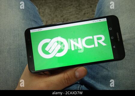 Homme tenant un smartphone avec le logo de NCR Corporation Banque D'Images