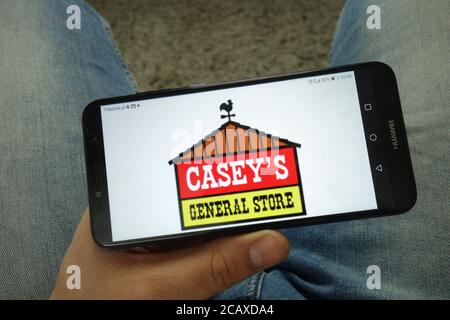 Homme tenant un smartphone avec le logo Casey's General Stores, Inc Banque D'Images