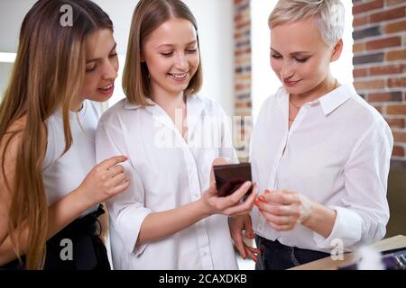 les jeunes femmes ont des conversations pendant la classe de maître dans le studio de beauté. une équipe amicale de visagistes se sont réunis pour partager des jetons de maquillage Banque D'Images