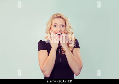 Bright blond woman holding mains sur les joues et des cris d'excitation et de bonheur Banque D'Images