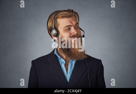 Profil latéral portrait of smiling customer service representative smiling. Hipster barbu dans l'homme d'affaires gris casque isolé sur gre Banque D'Images