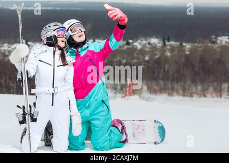 deux belles femmes filant une vidéo pendant les vacances d'hiver, blogueur à la station, sportswomen se reposent sur une chaude journée d'hiver Banque D'Images