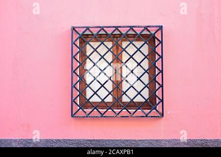 Fenêtre carrée barrée dans une façade rose pâle d'une élégante maison de villa européenne. Banque D'Images